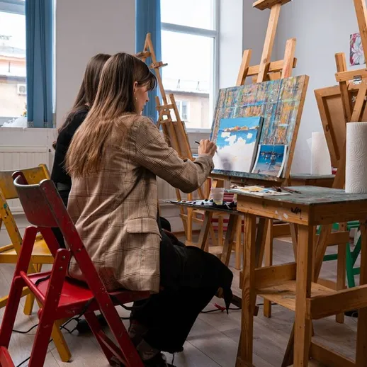 Две художницы создают картины в художественной студии с деревянными мольбертами и естественным светом