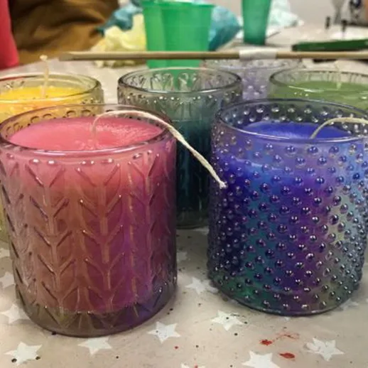 Яркие свечи в стеклянных банках, созданные на мастер-классе по изготовлению свечей