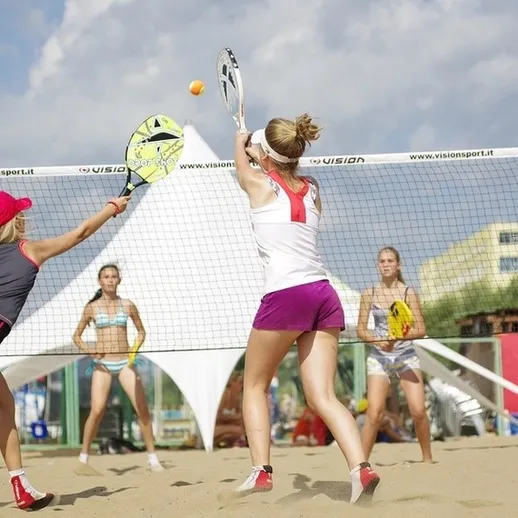 Две девушки играют в пляжный теннис на песчаном берегу в солнечный день