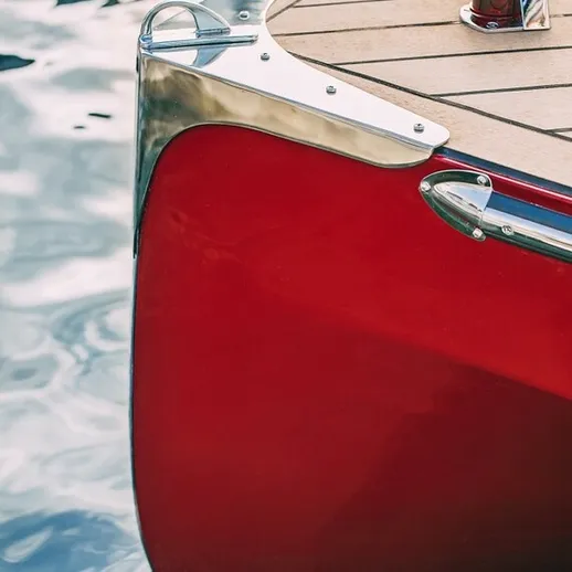 Ярко-красная лодка на воде с металлическими элементами в солнечный день