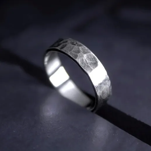 Металлическое кольцо с рельефной поверхностью на темном фоне, освещенное мягким светом