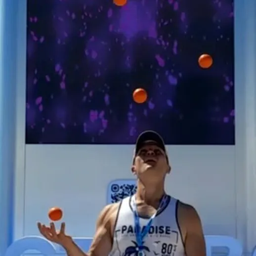 Уличный жонглер демонстрирует свои навыки с оранжевыми мячами на фестивале в солнечный день