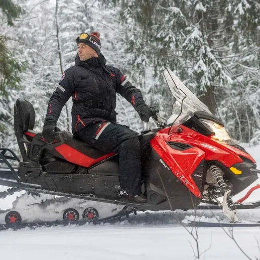 Мужчина ездит на снегоходе по лесу в зимний день