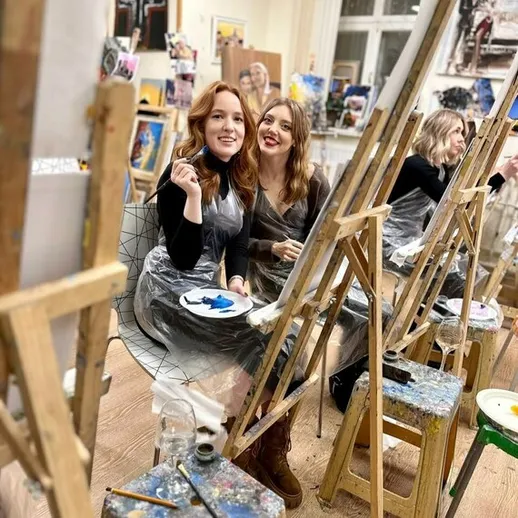 Две художницы наслаждаются процессом рисования в студии арт-класса вечером