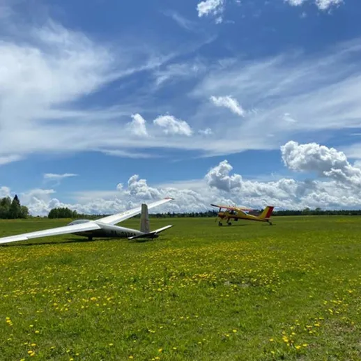 Самолет и планер на зеленом поле под голубым небом в солнечный день