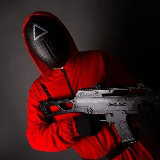 Тайный участник соревнований с оружием в красном костюме на фоне черного пространства