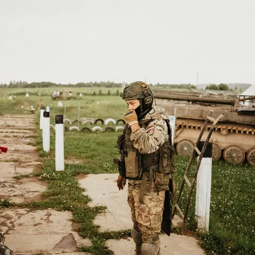 Военные на учениях в поле, мужчина в камуфляже и солдат в бронежилете, рассказывают о стратегии и подготовке