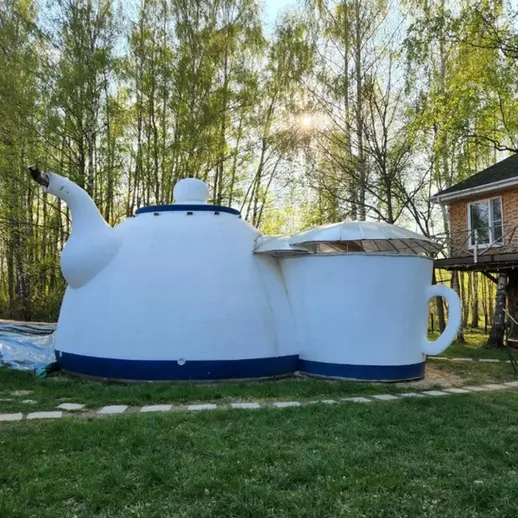 Огромный чайник на даче среди зелёных деревьев в солнечный день