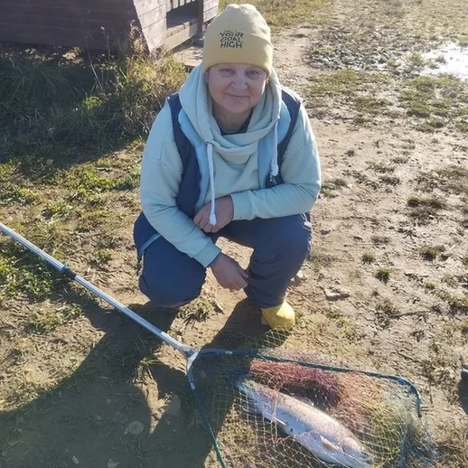 Женщина, ловящая рыбу на реке в солнечный осенний день
