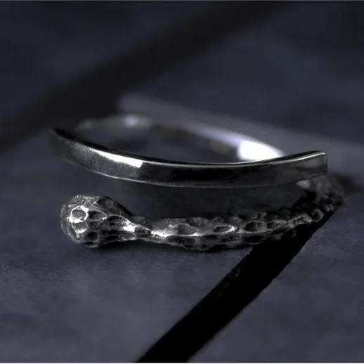 Серебряное кольцо с оригинальным дизайном, размещенное на темной поверхности