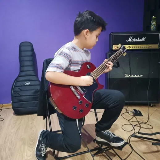 Молодой музыкант играет на электрогитаре в репетиционной студии