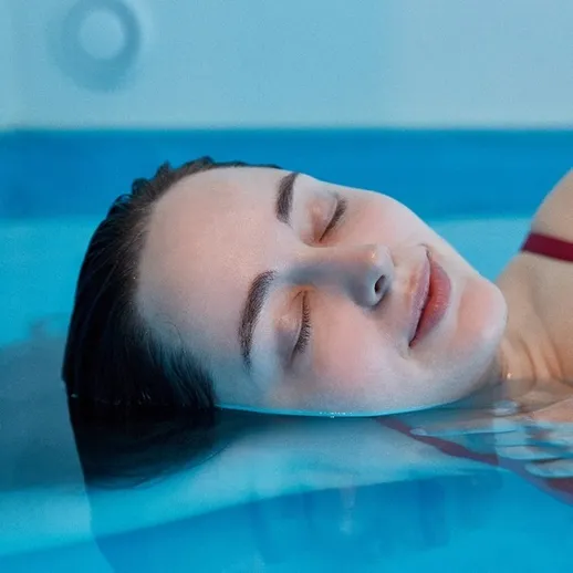 Женщина расслабляется в прозрачной воде бассейна в спокойной обстановке
