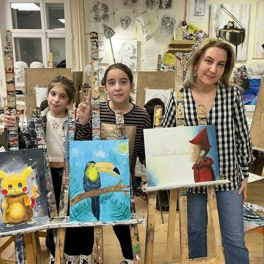 Дети и учитель искусства в художественной студии во время занятия по рисованию в зимний вечер