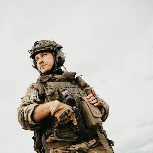 Военный в форме стоит на фоне неба и наблюдает за окружающей обстановкой в условиях выполнения заданий