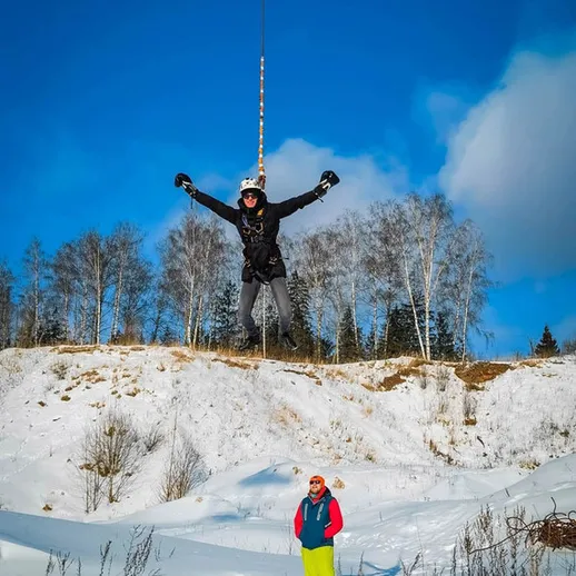 Захватывающий вираж на зимнем лыжном курорте, мужчина разгоняется с горы, с белыми деревьями на фоне
