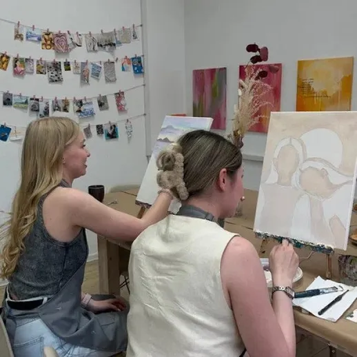 Две женщины рисуют картины в художественной студии во время занятия по живописи