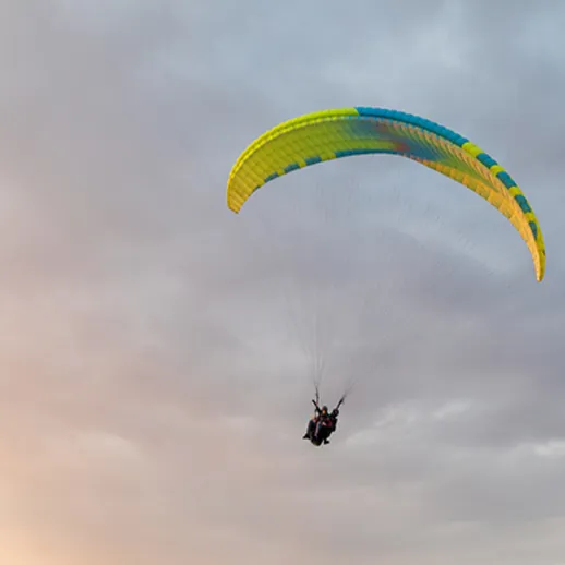Парапланеристы в полете над облаками во время заката в группе единомышленников