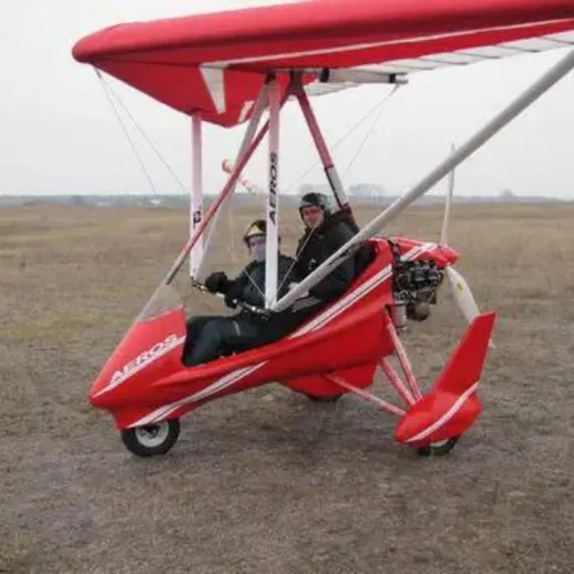 Летательный аппарат красного цвета на открытом поле с пилотом и пассажиром в зимнее время