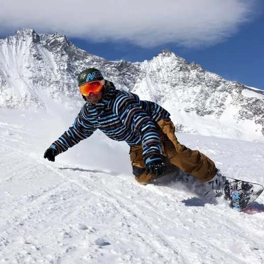 На заснеженных склонах горного района человек катается на сноуборде под ясным небом в солнечный зимний день