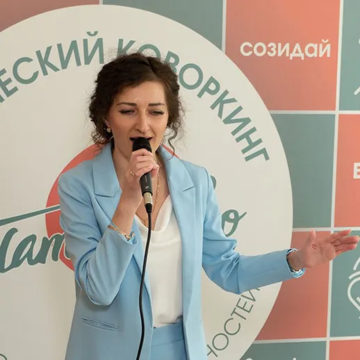 Женщина поет в синем костюме на мероприятии в Ханты-Мансийске в уютной обстановке