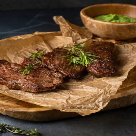 Ароматное мясо на деревянной доске с соусом из авокадо и зеленью в уютной обстановке