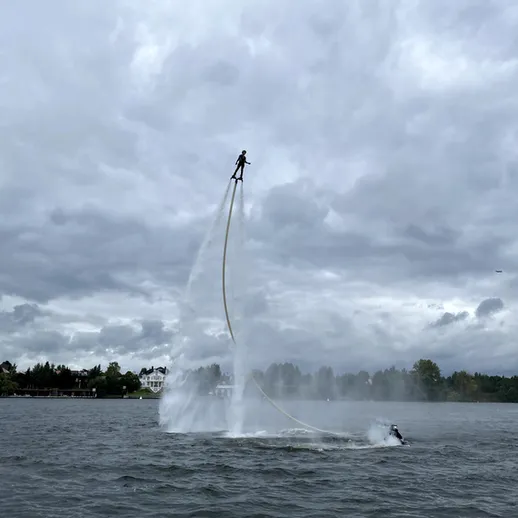 Человек на водном реактивном ранце поднимается над озером во время облачного дня