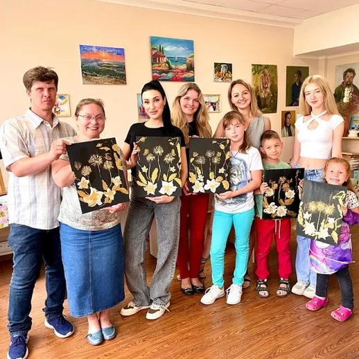 Группа детей и взрослых показывает свои картины на художественном занятии в студии