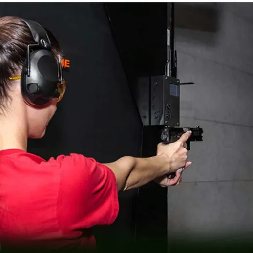 Женщина тренируется стрельбе в тире с пистолетом во время вечернего занятия в большом городе