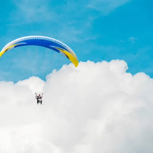 Парапланерист наслаждается полетом над облаками в ясный день с ярким небом