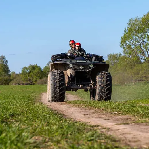 Катание на квадроцикле по живописной местности в солнечный день на фоне зелёных деревьев