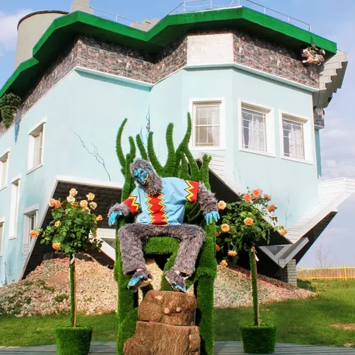 Уникальный дом, стоящий на крыше, с фигурой из зелени и цветов в солнечный день