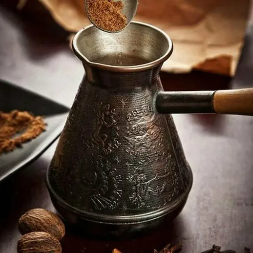 Процесс приготовления кофе в традиционной турке с пряностями на кухонном столе