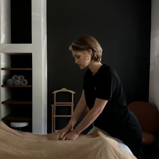 Массажист делает расслабляющий массаж на столе в уютном салоне в вечернее время