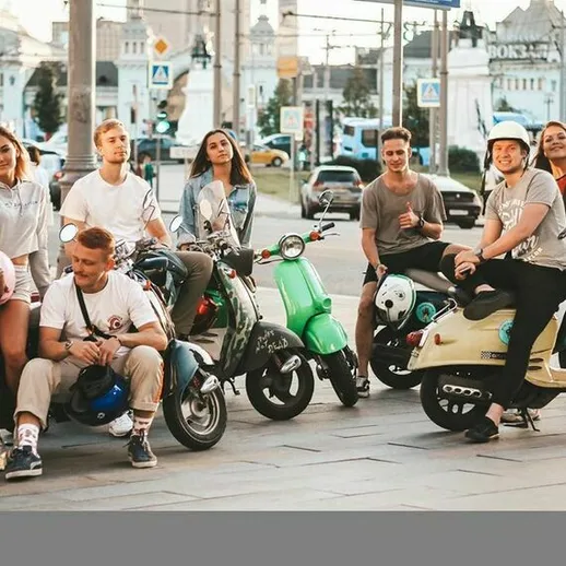 Группа друзей наслаждается прогулкой на электроскутерах в центре города в солнечный день