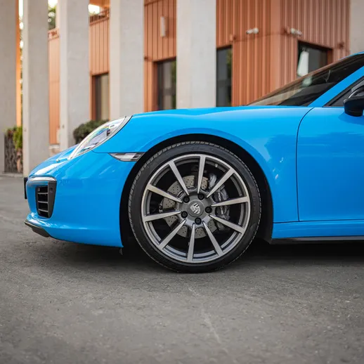 Синий автомобиль стоит на асфальте рядом с зданием в ясный день