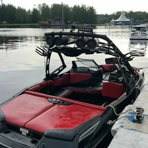 Судно для водных видов спорта у причала в спокойный вечер на озере, окруженное зелеными деревьями