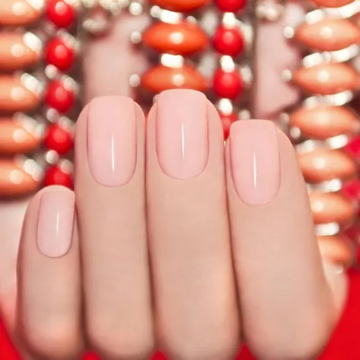 Нежный маникюр с пастельным цветом на фоне ярких украшений и красной ткани