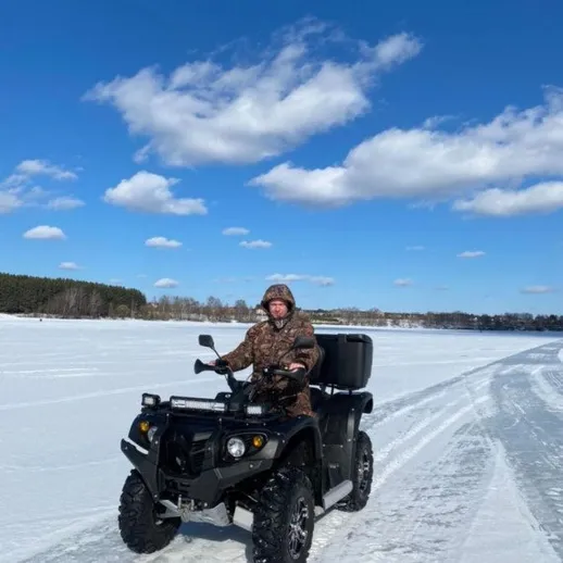 Мужчина на квадроцикле по снежному полю в ясный день