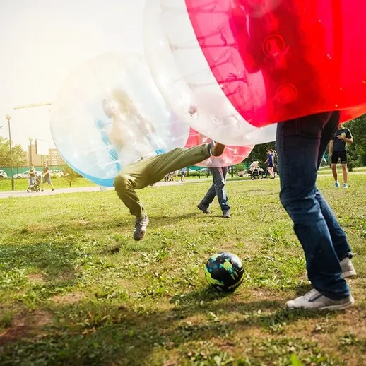 Игроки в надувных шарах ведут активные конкурсы на травяном поле в парке