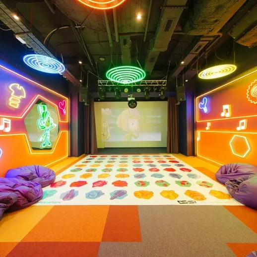 Интерактивное помещение для развлечений с яркими неоновыми огнями и уютными пуфами, подходящее для детей и взрослых