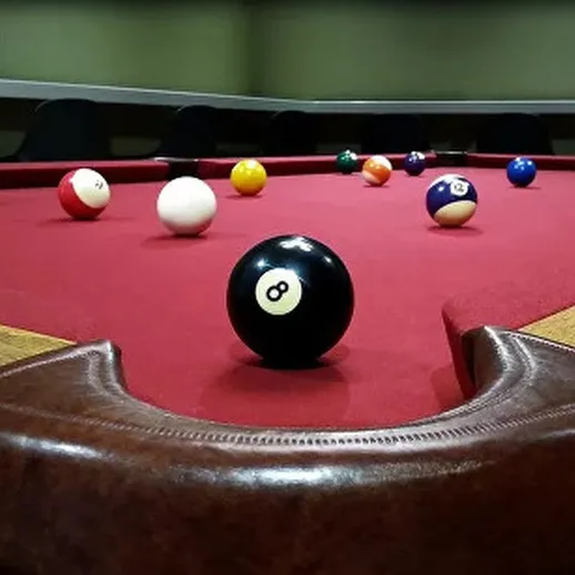 Стол для бильярда с шарами и черным шаром восьмеркой в помещении клуба