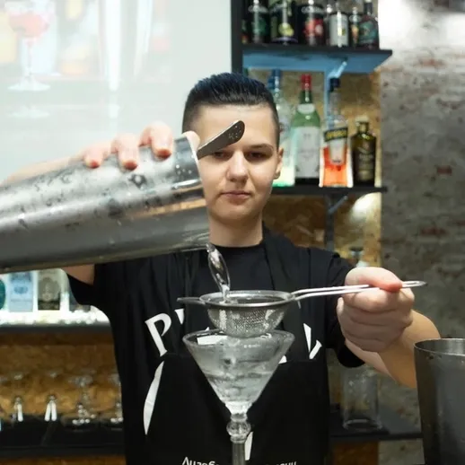 Молодой бармен готовит коктейль в стильном баре, Москва, вечер