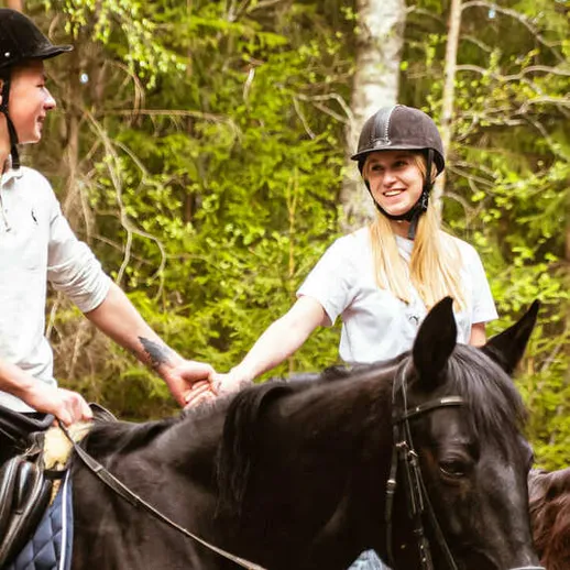 Наездницы наслаждаются верховой ездой в лесу во время теплого весеннего дня Наездницы наслаждаются верховой ездой в лесу во время теплого весеннего дня