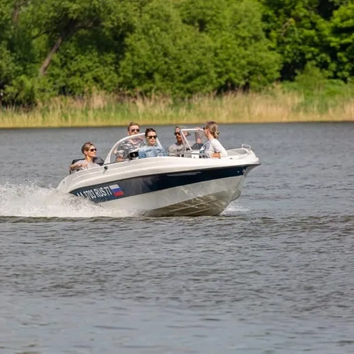 На речном катере группа людей наслаждается солнечным днем на реке в живописной местности