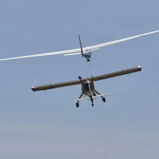 Два самолета в воздухе: планер и спортивный самолет над облаками в ясный день