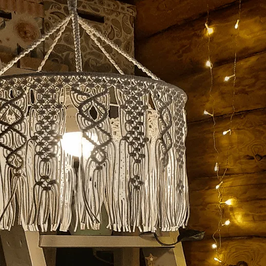 Уютный интерьер с макраме светильником и праздничными огнями в деревянном доме