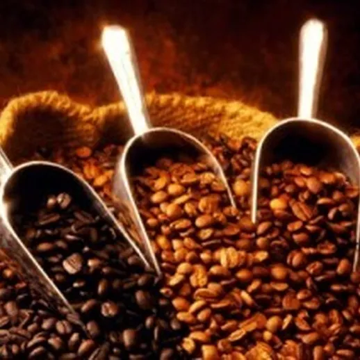 Кофейные зерна в мешке с ложками на фоне теплого света