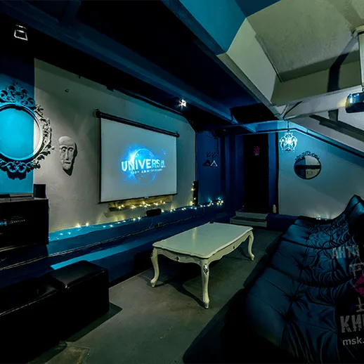 Уютный домашний кинотеатр с проектором и комфортной мебелью в темном интерьере