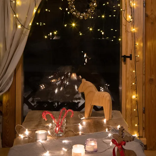 Уютный зимний вечер у окна с гирляндами, свечами и декоративными элементами