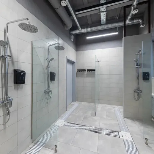 Душевая комната в тренажерном зале с стеклянными перегородками и сантехникой